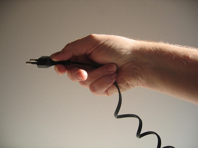 Hand hält Stromstecker eines Verlängerungskabels